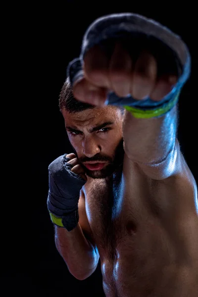 El boxeador está listo para dar un golpe poderoso. Foto de un hombre musculoso con manos fuertes y puños apretados en rayas azules sobre fondo negro . — Foto de Stock