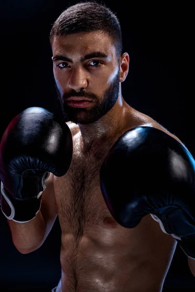 Forte boxeador muscular em luvas de boxe preto. Um homem em uma banca de boxe em fundo preto . — Fotografia de Stock