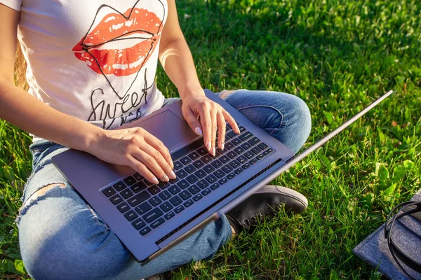 Закройте руки на клавиатуре. Женщина работает на ноутбуке компьютер в парке на зеленой лужайке лужайка солнечного света на открытом воздухе . — стоковое фото
