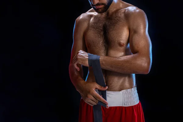 Boxeadora preparando sus guantes para una pelea. Foto de un hombre musculoso atando las manos sobre fondo negro . —  Fotos de Stock