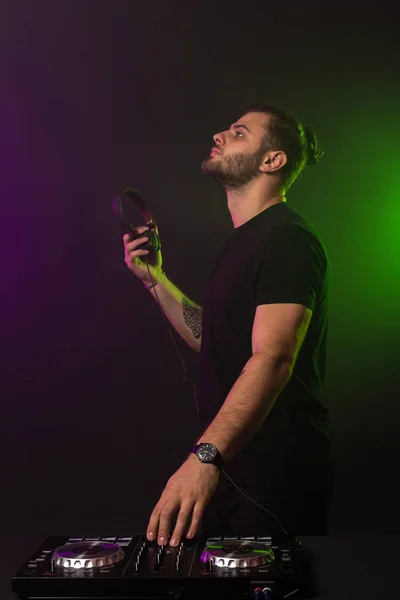 DJ παίζει μουσική στο μίξερ σε πολύχρωμα ομιχλώδες φόντο — Φωτογραφία Αρχείου