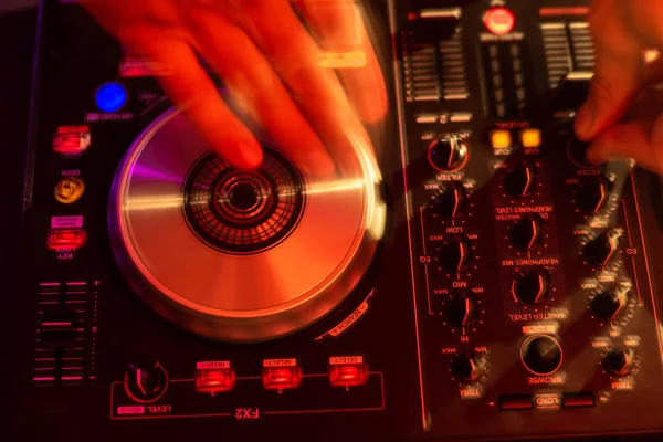 Dj mixing on turntables with color light effects. Soft focus on hand. Close-up.