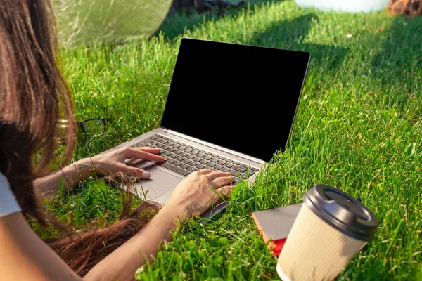 Zblízka ruce na klávesnici. Žena pracující na pc notebooku s prázdnou černá prázdná obrazovka kopírování prostoru v parku na zelené trávě sluníčko trávníku venku. — Stock fotografie