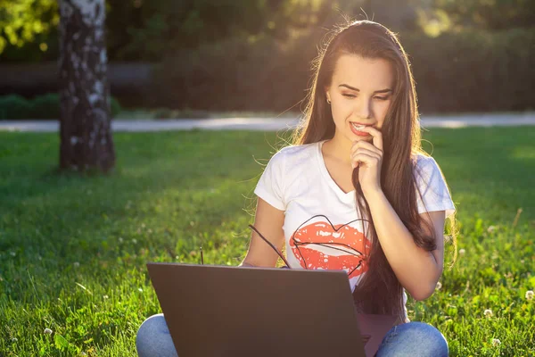 Jeune femme utilisant un ordinateur sur les herbes vertes dans le parc. Éducation apprentissage ou freelance travailler en plein air ou de détente concept idée arrière-plan. Éclair de soleil — Photo
