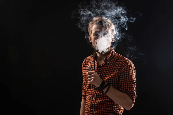 Un joven con barba y un peinado elegante con camisa, fumando un cigarrillo, una víbora, una habitación, un estudio, humo, disfrute — Foto de Stock