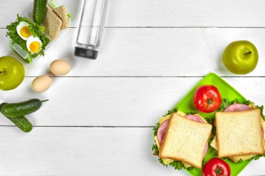 Öğle Yemeği. Şişe su ve yeşil elma ahşap masa üzerinde yeşil plaka sandviç ve taze sebze ile. Sağlıklı beslenme kavramı. Üstten görünüm