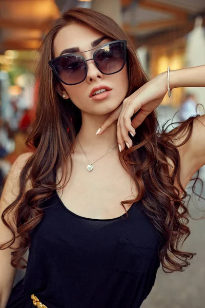 Közeli kép: portré fiatal elegáns barna-fekete ruha és a napszemüveg, megható az arcát. Utcai divat-shot — Stock Fotó