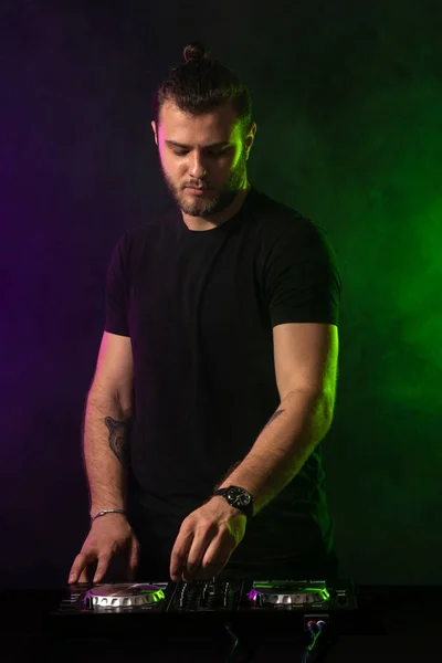 DJ tocando música en el mezclador sobre fondo brumoso colorido — Foto de Stock