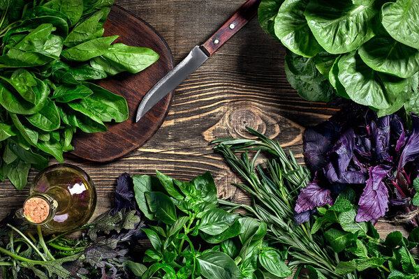 Variety of fresh organic herbs on wooden background. Freshly harvested herbs including basil, arugula. Top view. Copy space.