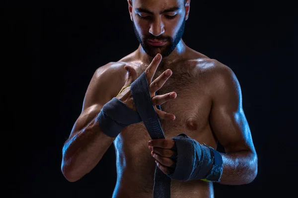 Boxer förbereder hennes handskar för en kamp. Foto av muskulös man band händerna på svart bakgrund. — Stockfoto