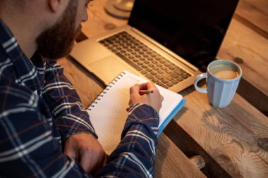 Geçici iş adamı veya serbest meslek sahibi eserleri üstünde defter, planlama ile akıllı telefon, kahve kahve dükkanı veya ev ofis, masada dizüstü bilgisayar üzerinde çalışan görüntü kırpılmış.