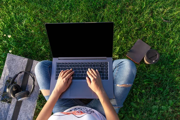 Vista dall'alto. Donna che lavora su computer portatile pc con schermo vuoto nero vuoto per copiare lo spazio nel parco su erba verde prato all'aperto . — Foto Stock