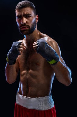 Savaşmaya hazır boksörü. Boksör güçlü eller ve siyah bir arka plan mavi askıları sıkışık yumruk ile