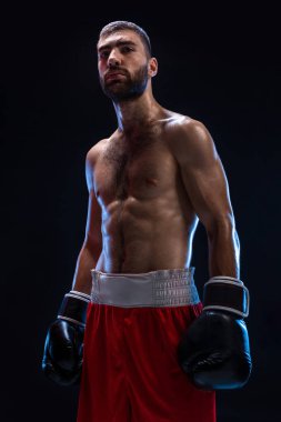 Atletik yakışıklı olan siyah bir zemin üzerine kırmızı şortla. Sonra uygulamak için kanca oluşturur ve darbeler boksör onun nefes alma.