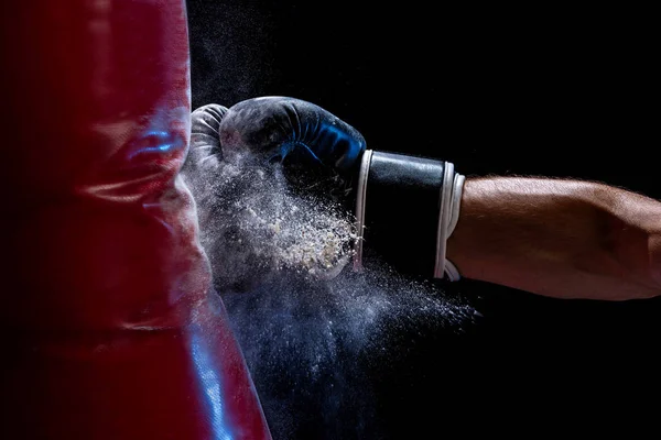 Close-up hand of boxer at the moment of impact on punching bag over black background — Stock Photo, Image