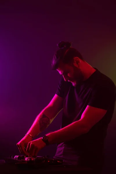 Atractivo joven DJ jugando en los tocadiscos con efectos de luz de color — Foto de Stock
