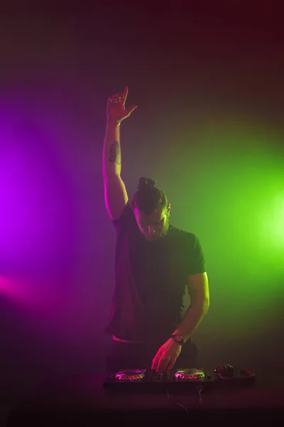 DJ στην εργασία μίξη ήχου για τα καταστρώματα σε μια λέσχη κόμμα ή νύχτας με πολύχρωμα καπνού ανοιχτό φόντο — Φωτογραφία Αρχείου