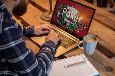 Genç adam tatilinde iş-kahve dükkanı, önünde açık dizüstü bilgisayar oturan erkek netbook ile poker oynamaya.