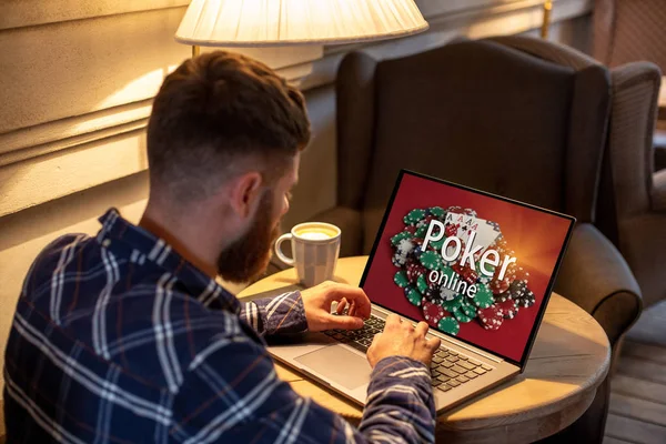 Jonge man spelen van poker via netbook tijdens werk-pauze in de coffeeshop, mannelijke zitten vooraan opengeklapte laptopcomputer. — Stockfoto