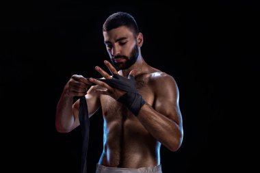 Boxer onun eldiven için bir mücadele hazırlanıyor. Kaslı adam şeritleme fotoğrafı siyah arka plan üzerine eller.