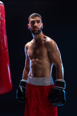 Atletik yakışıklı olan siyah bir zemin üzerine kırmızı şortla. Sonra uygulamak için kanca oluşturur ve darbeler boksör onun nefes alma.