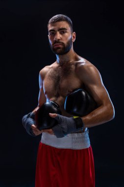 Atletik yakışıklı olan siyah bir zemin üzerine kırmızı şortla. Sonra uygulamak için kanca oluşturur ve darbeler boksör onun nefes alma.