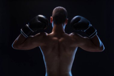 Dikiz güçlü genç erkek boxer. Siyah arka plan üzerinde duran boks eldivenli fitness erkek modeli.