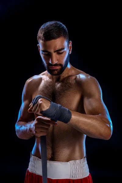 Boxeadora preparando sus guantes para una pelea. Foto de un hombre musculoso atando las manos sobre fondo negro . — Foto de Stock
