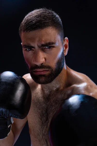 Porträt eines harten männlichen Boxers, der in Boxhaltung vor schwarzem Hintergrund posiert. — Stockfoto