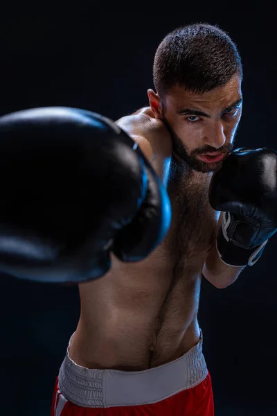 Porträt eines harten männlichen Boxers, der in Boxhaltung vor schwarzem Hintergrund posiert. — Stockfoto
