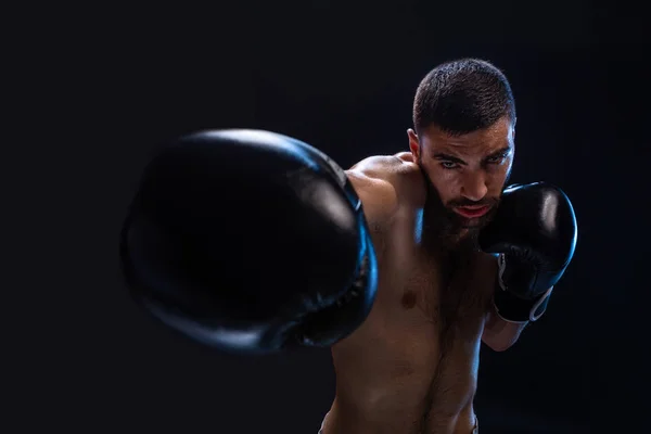 O homem está a bater num adversário. Caça focada com tronco nu e luvas de boxe olhando para a câmera. Ganhar . — Fotografia de Stock