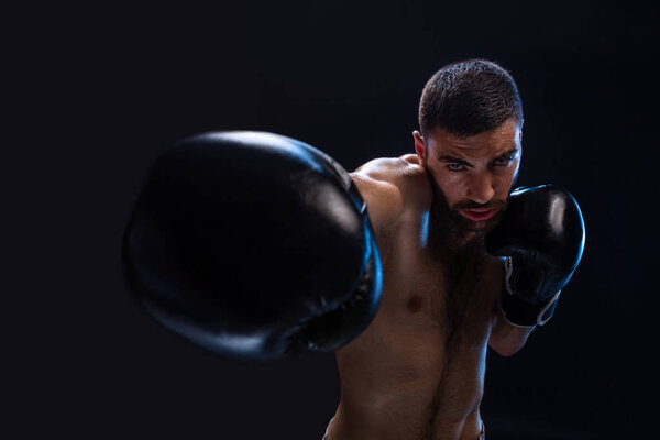 Человек бьет противника. Фокусный боец с обнаженным туловищем и боксерскими перчатками, смотрящий в камеру. Победа
.