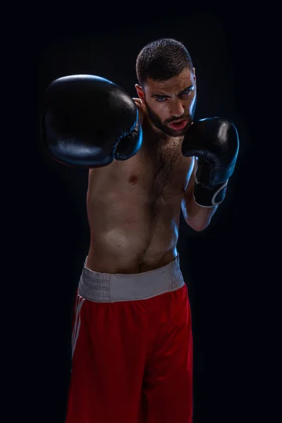 El boxeador está listo para dar un golpe poderoso. Foto de hombre musculoso sobre fondo negro . — Foto de Stock