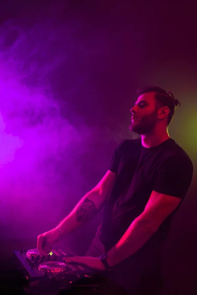 Atractivo joven DJ jugando en los tocadiscos con efectos de luz de color — Foto de Stock