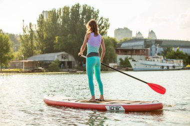 Kadın bir Sup tahta üzerinde güneşli sabahı ölü olarak yatıyor. Yukarı raket yatılı - stand tatil sırasında harika Aktif istirahat.
