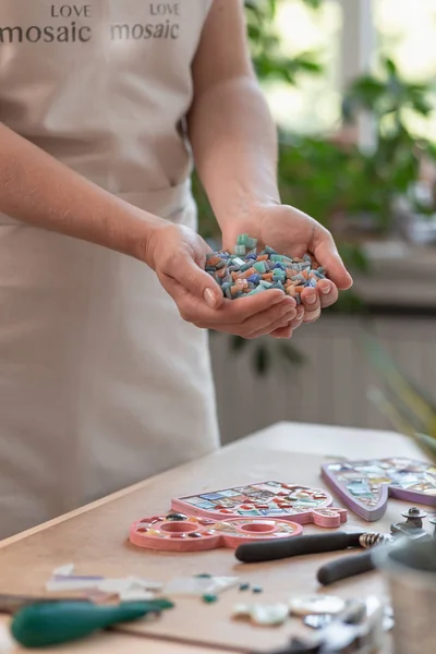 Local de trabalho do mestre do mosaico: mãos das mulheres segurando detalhes em mosaico no processo de fazer um mosaico — Fotografia de Stock