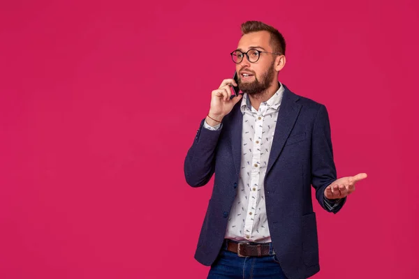 Joven abogado alegre o hombre de negocios está de pie sobre el fondo rosa y sonriendo, hablando por teléfono —  Fotos de Stock