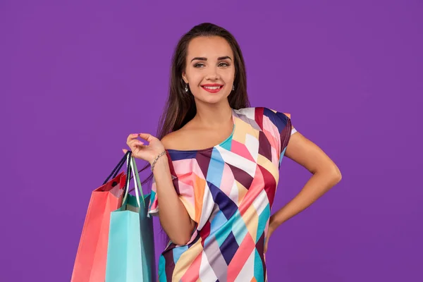 Hermosa mujer joven con coloridas bolsas de compras en el maravilloso fondo púrpura — Foto de Stock