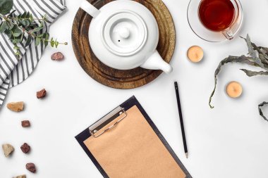 Beyaz arka plan üzerinde hangi Kraft kağıt, defter, fincan çay ve beyaz porselen demlik ile. Romantik kahvaltı. Üstten görünüm. Kopya alanı.