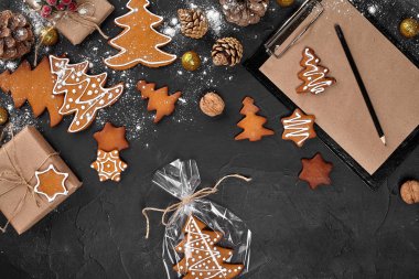 Karanlık bir tablo arka plan üzerinde ambalaj bir selofan bir Noel ağacı şeklinde bir Noel zencefilli kurabiye. Noel hediye kavramı.
