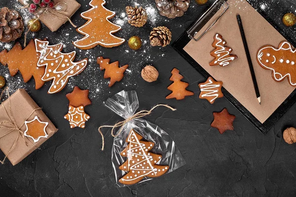 Um biscoito de gengibre de Natal na forma de uma árvore de Natal em uma embalagem de celofane no fundo de uma mesa escura. Conceito de presente de Natal . — Fotografia de Stock