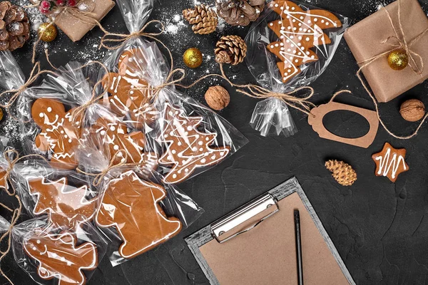 Um biscoito de gengibre de Natal na forma de uma árvore de Natal em uma embalagem de celofane no fundo de uma mesa escura. Conceito de presente de Natal . — Fotografia de Stock