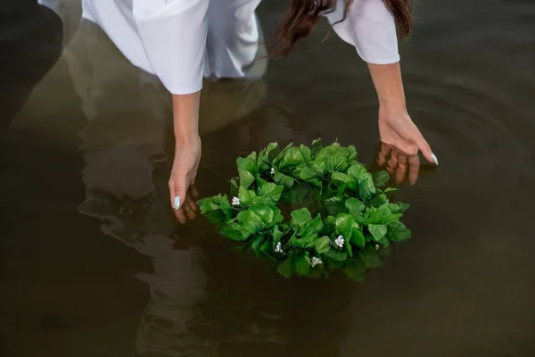 Close-up of woman in white dress in the water. Art Woman with wreath in river. Wet witch Girl in the lake