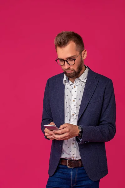 Estudio plano de atractivo hombre de negocios morena con gafas, en camisa casual, elegante chaqueta negra sosteniendo un teléfono inteligente —  Fotos de Stock