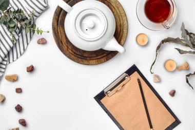 Beyaz arka plan üzerinde hangi Kraft kağıt, defter, fincan çay ve beyaz porselen demlik ile. Romantik kahvaltı. Üstten görünüm. Kopya alanı.