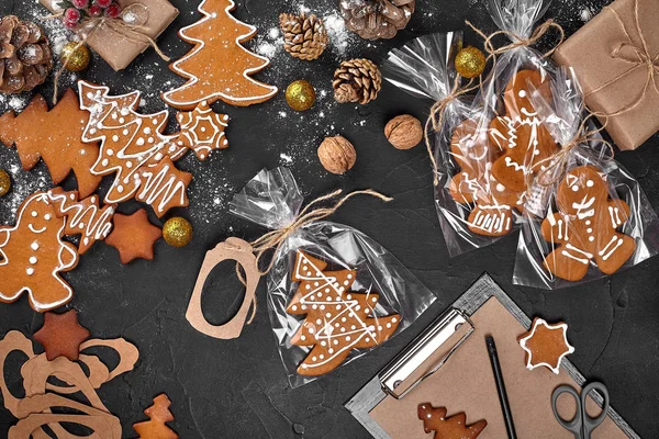 Um biscoito de gengibre de Natal na forma de uma árvore de Natal em uma embalagem de celofane no fundo de uma mesa escura. Conceito de presente de Natal . — Fotografia de Stock