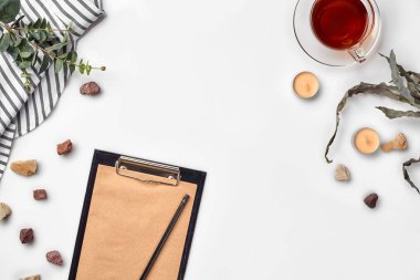 Beyaz tabloda çay ile boş açılan not defteri. Üstten görünüm. Yazma kavramı