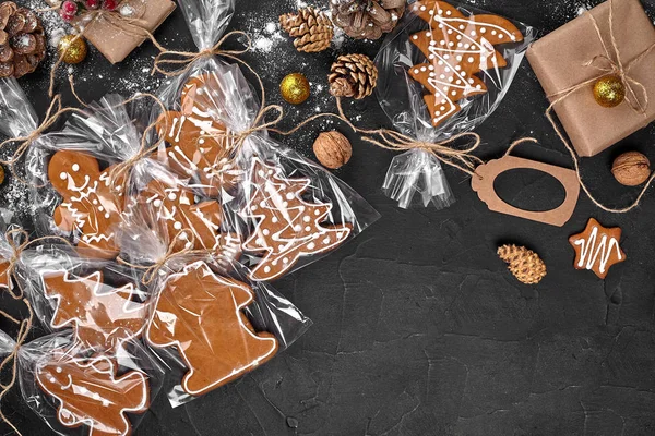 Um biscoito de gengibre de Natal na forma de uma árvore de Natal em uma embalagem de celofane no fundo de uma mesa escura. Conceito de presente de Natal . — Fotografia de Stock