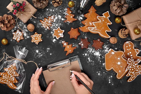 Árvore de biscoito de Natal feito com estrela cortador de biscoito bolo de gengibre ano novo decorado com arco de corda e forma para cortar biscoitos na mesa preta . — Fotografia de Stock