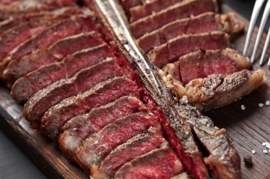 Ahşap tahta üzerinde yalan T-bone biftek dilimlenmiş. Yakın çekim
